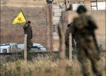 Kurdish YPG fighters hold their movement's flag