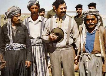 Former Iraqi President Saddam Hussein (C) holds the hand of a man as he poses for a picture with a group of Kurdish farmers in Iraqi Kurdistan, the northern part of Iraq, 1980s. Photo: From the private archive of an official photographer for the regime/via Reuters