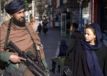 A Taliban fighter stands guard as a woman walks past in Kabul, Afghanistan, December 26, 2022. Photo: AP