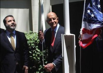 Syrian Foreign Minister Asaad Hassan al-Shibani stands next to U.S. envoy for Syria Thomas Barrack as he raises the American flag at U.S. ambassador's residency in Damascus, Syria. May 29, 2025. Photo: Reuters