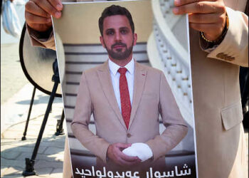 A supporter holds a poster of Shaswar Abdulwahid, leader of the New Generation Movement (Cûłanewey Newey Nwê), outside the Sulaimani Court building in Iraqi Kurdistan, August 2025. Photo: Channel8.com