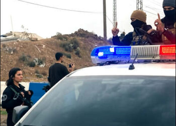 Members of Syrian government Islamist forces make provocative gestures imitating ISIS fighters toward a female Kurdish YPJ/YPG fighter as they enter the Kurdish city of Qamishlo in Rojava, Syrian Kurdistan, on February 3, 2026. Photo: iKurd.net/X