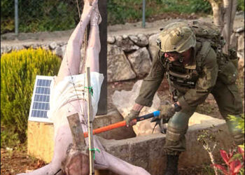 Israeli soldier damages the head of a statue of Jesus, in Debel, Lebanon