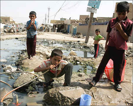 Iraqi boy drinking water pipe Sadr City Baghdad Iraq children people 2015 poor people