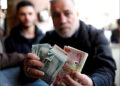A man holds money at a foreign currency exchange market in Baghdad, Iraq People Iraqi dinar dollar cash