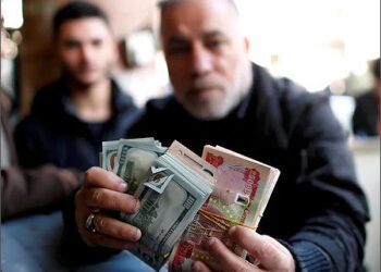 A man holds money at a foreign currency exchange market in Baghdad, Iraq People Iraqi dinar dollar cash