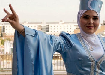 Turkmen woman wearing a hat with a Turkmen Front flag on the front, gestures the Turkish nationalist “Grey Wolf” sign at Erbil Citadel, Iraqi Kurdistan